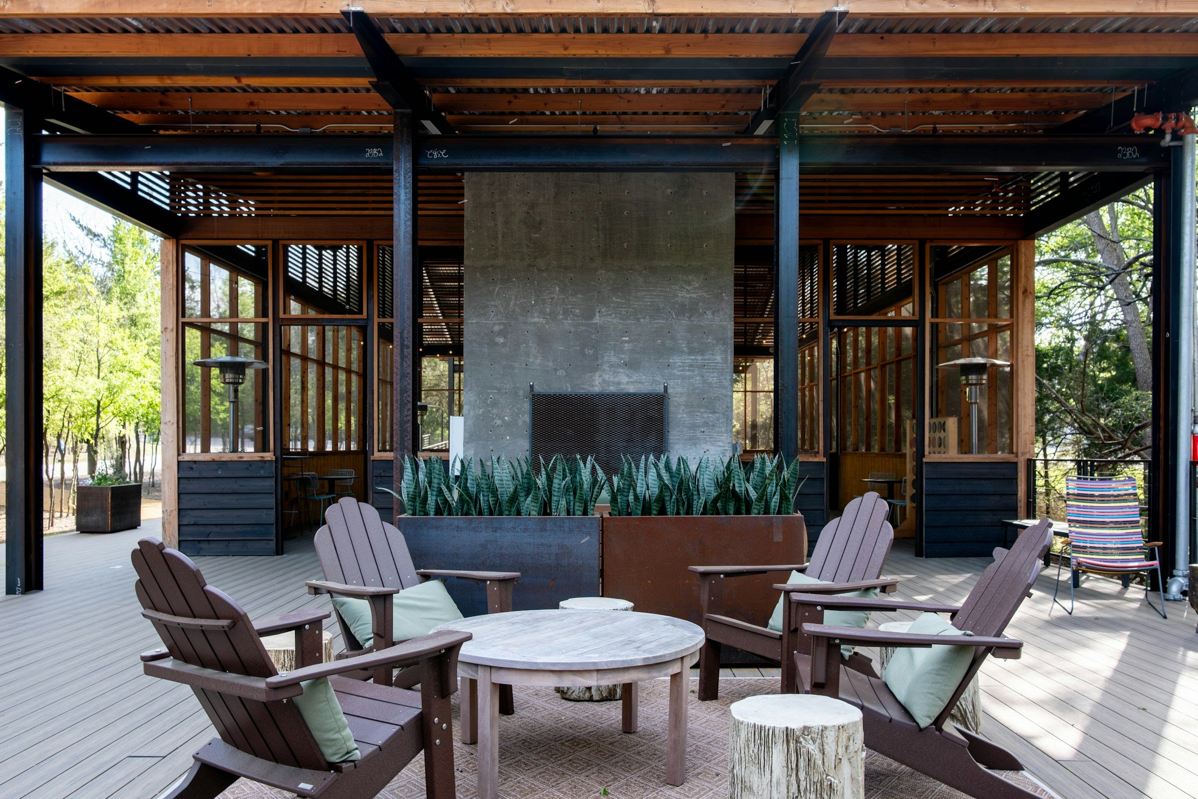 Outdoor patio with stone fireplace and Adirondack chairs